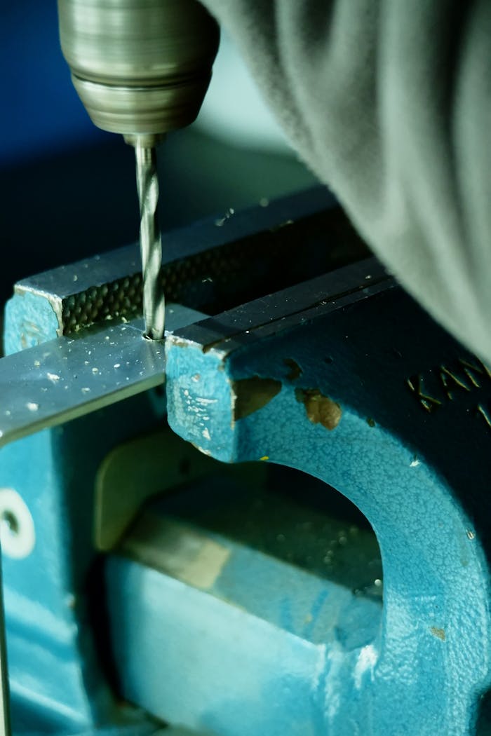 Focused shot of a drill working on a metal piece in a workshop setting.