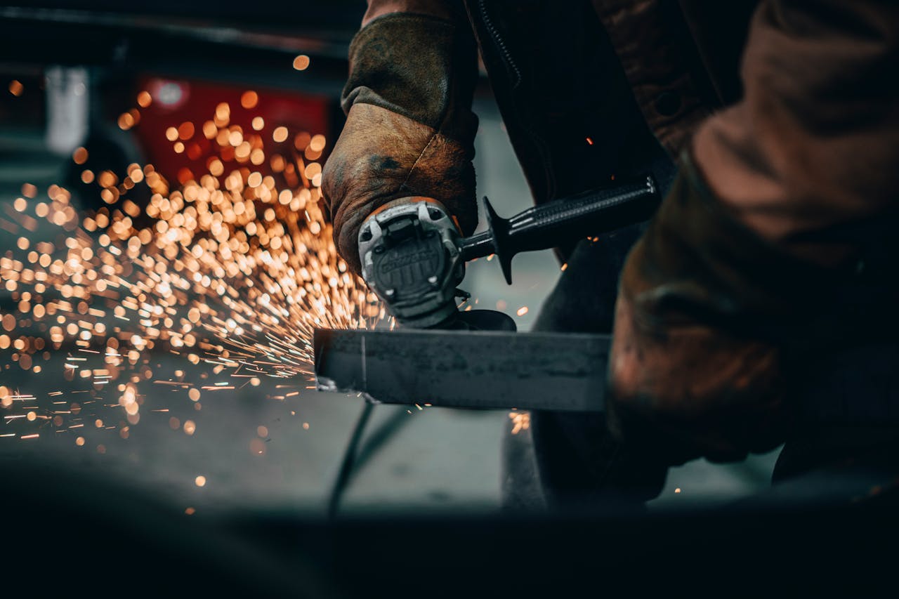 Close-up of a worker using an angle grinder, generating sparks in a factory setting.